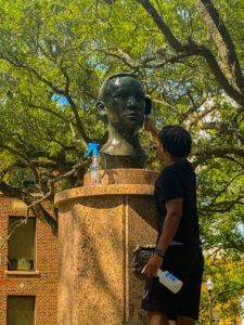 Malachi McMahon cleaning the Abner Davis memorial with a bristle brush and cleaning solution.