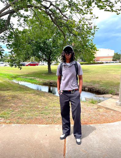 Student standing on sidewalk near water feature outside of campus student center.