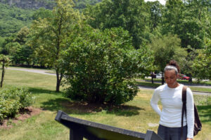 Girl standing infront of seneca rock reading about a homestead on the property