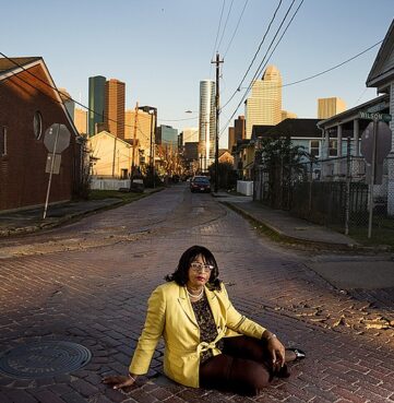 A lady sitting in the street where there are public issues