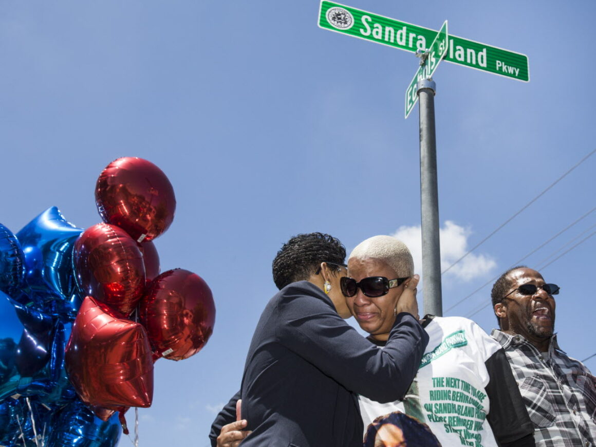 Several women crying in front of street sign