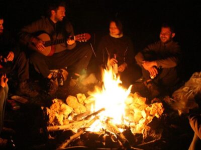 A group of people sitting around a fire telling stories and singing songs