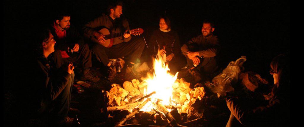 A group of people sitting around a fire telling stories and singing songs