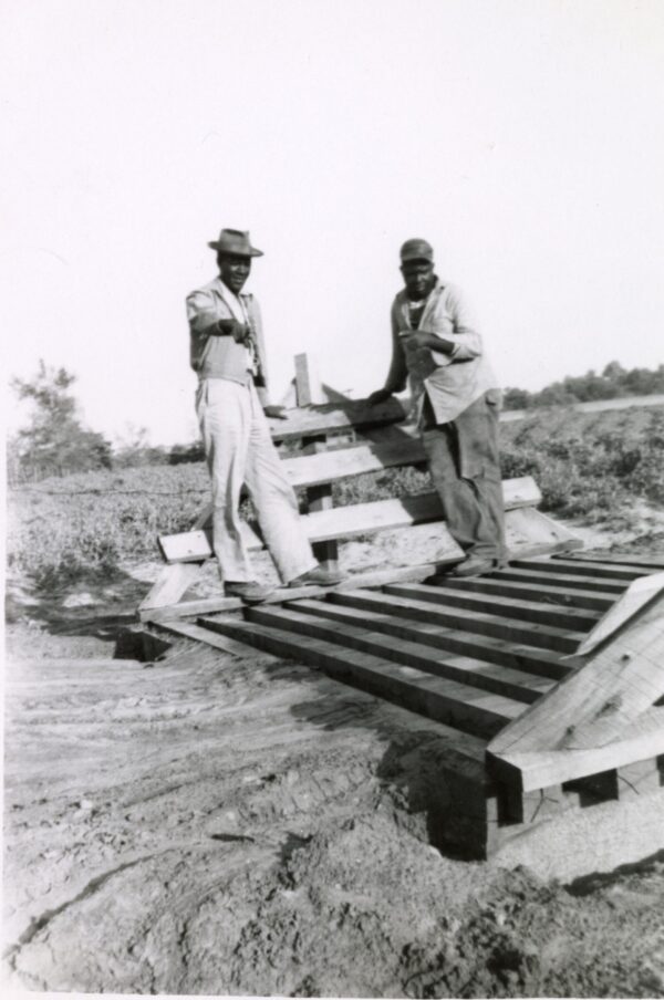 Tom Lacy showing R.P. Gooden the cattle guard he built in 1953 Rusk County [PVAMU Archives, Texas Black CE&HD Collection, Rusk County, Box 4, Folder22]